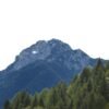 Breathtaking view of a majestic mountain peak surrounded by a lush green forest under a clear sky.